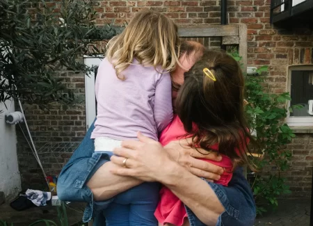 An adult hugging two young children